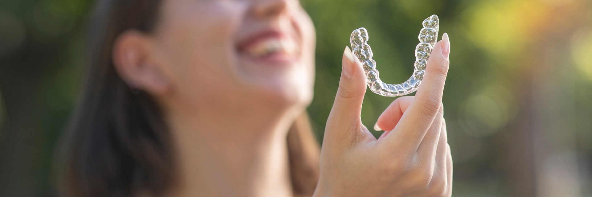woman smiling holding clear aligner